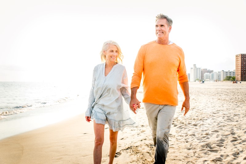 A mature couple enjoying a walk on a Florida beach after having spider vein treatment in Sarasota